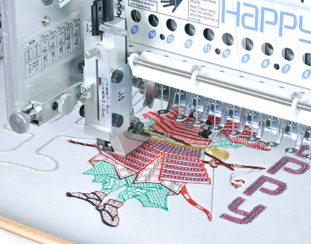 Happy Mehrkopf-Stickmaschine bestickt einen bunten Ahornblatt-Anhänger auf hellem Stoff